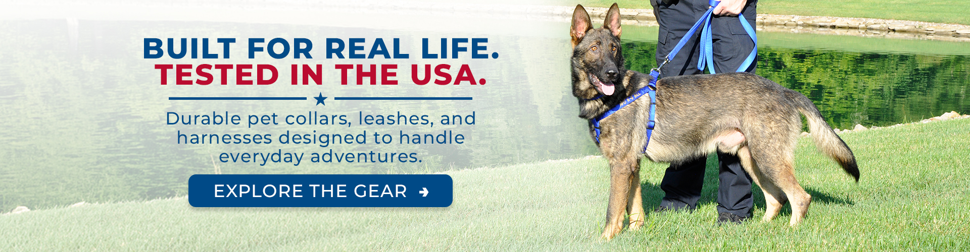 German Shepherd wearing a blue harness and leash stands on green grass beside a pond, held by a person partially visible at the edge of the frame. Overlay text reads: “Built for real life. Tested in the USA. Durable pet collars, leashes, and harnesses designed to handle everyday adventures.” A button says “Explore the gear.”