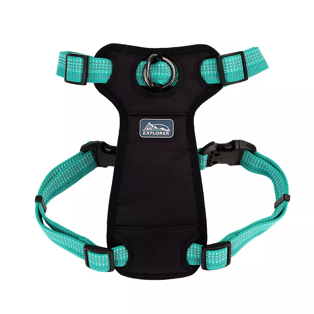 A teal and black front‑connect dog harness is displayed against a white background. The harness features teal woven straps with reflective stitching and black edge trim. A black padded chest panel supports the strap structure. Black plastic slide adjusters and black plastic side‑release buckles are integrated into the straps. A metal D‑ring is positioned at the center of the front chest panel. Two small reflective patches appear on the upper strap sections.